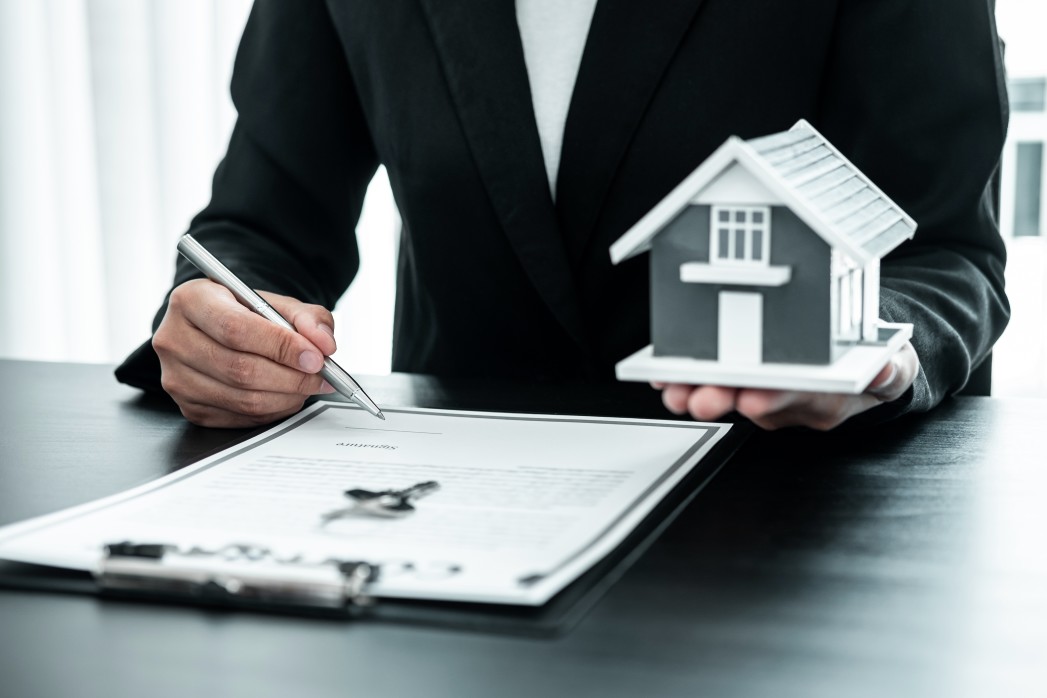 aplicabilidade do cdc em contratos de venda com alienação fiduciária - advogado segurando uma casa e uma caneta